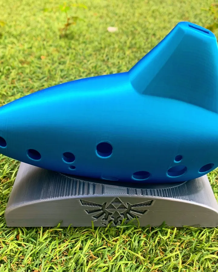 Réplica da Ocarina do Tempo impressa em 3D em azul, sobre base com o brasão